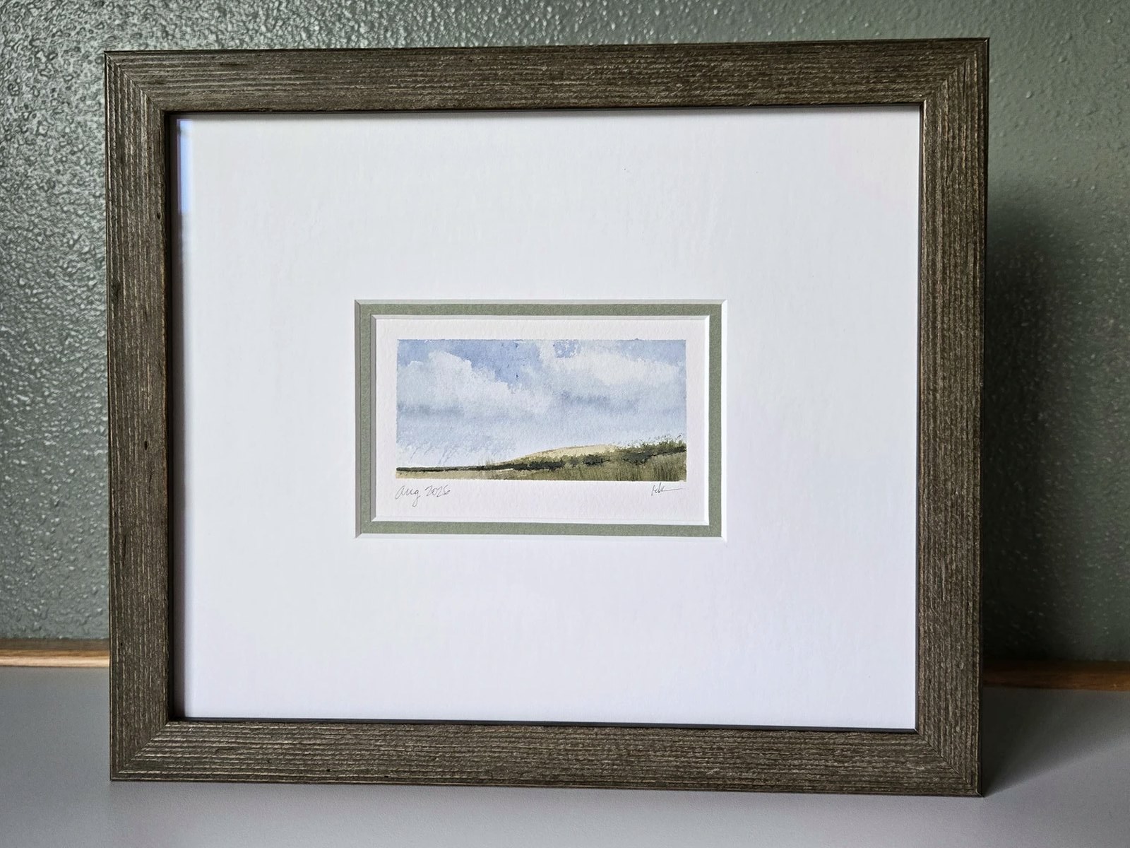 A hand-painted card from the studio, framed with a generous mat and rustic wood frame