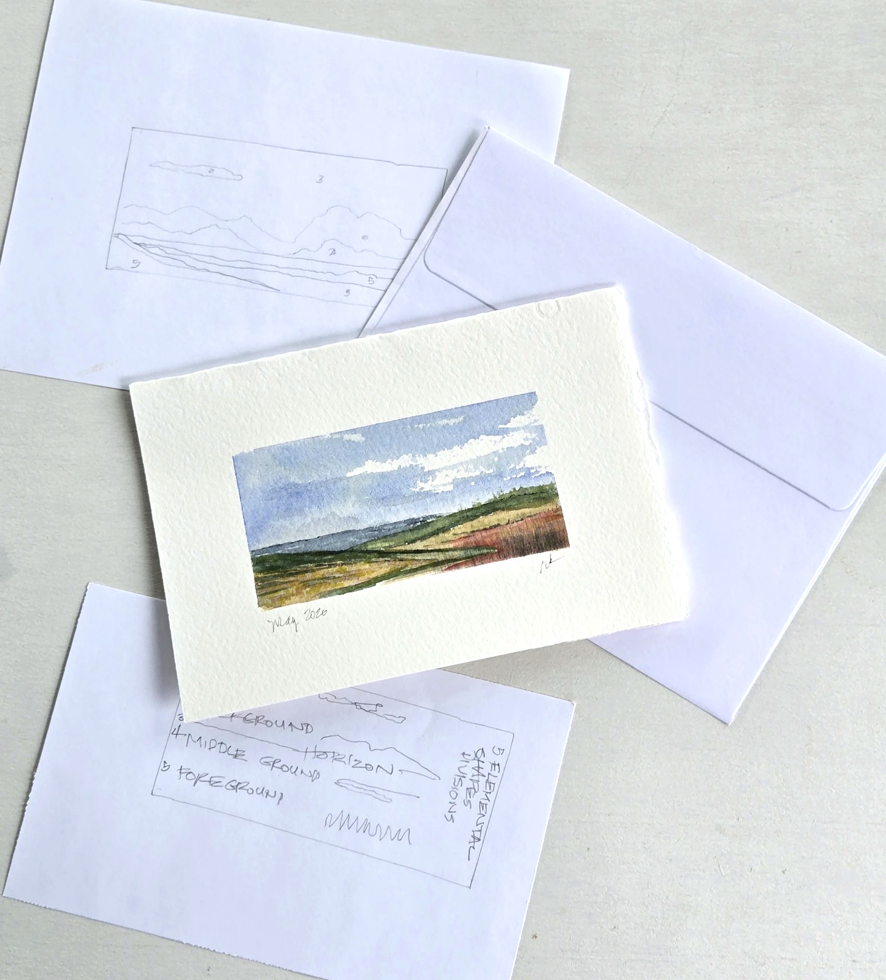 From field sketch to finished card — the working table with notes, card, and envelopes