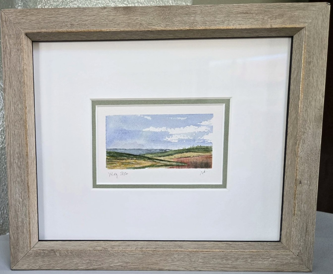 The finished watercolor, framed with a wide mat and wood frame
