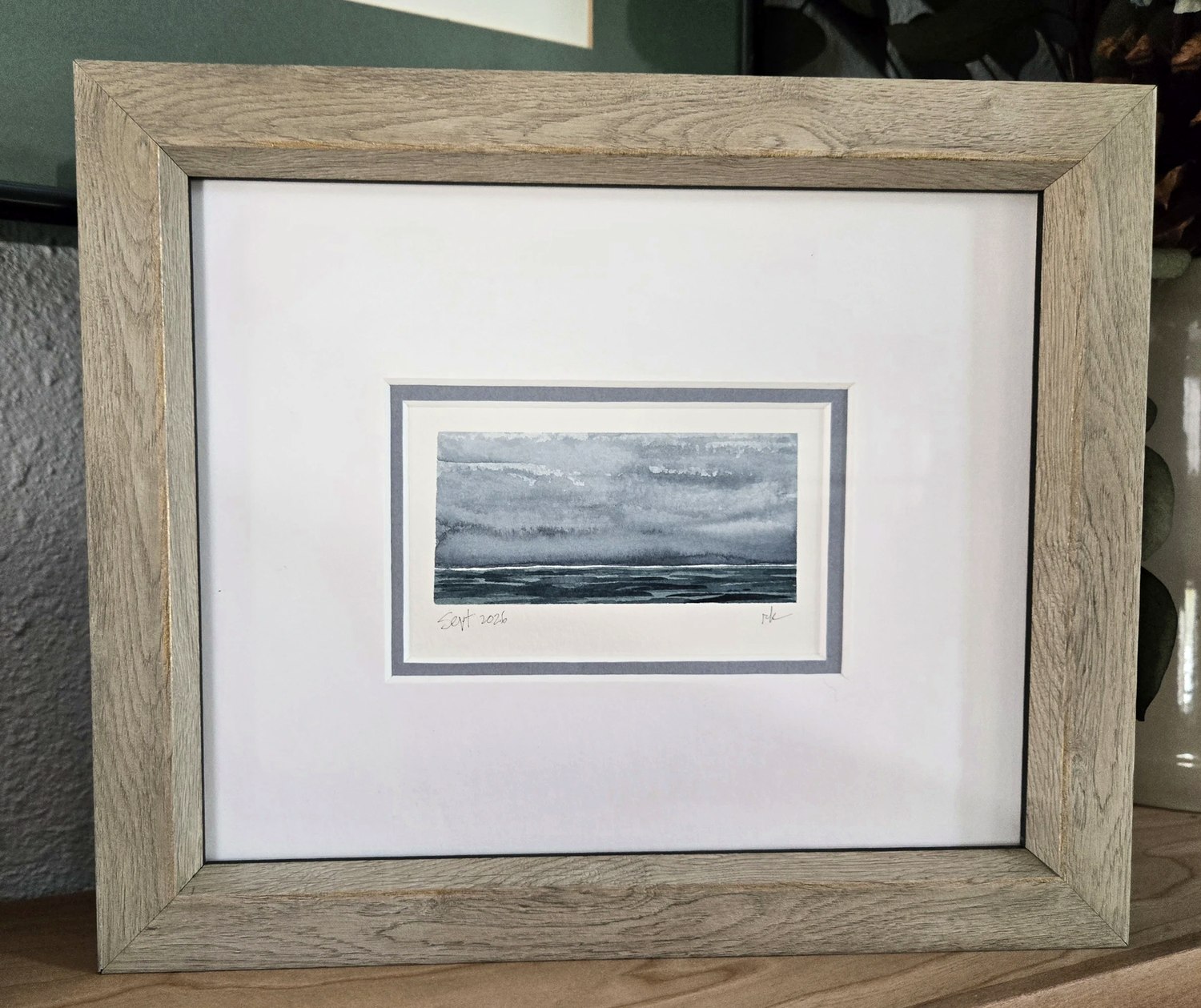 The September grey-sea watercolor, framed with a wide mat and slate inner border