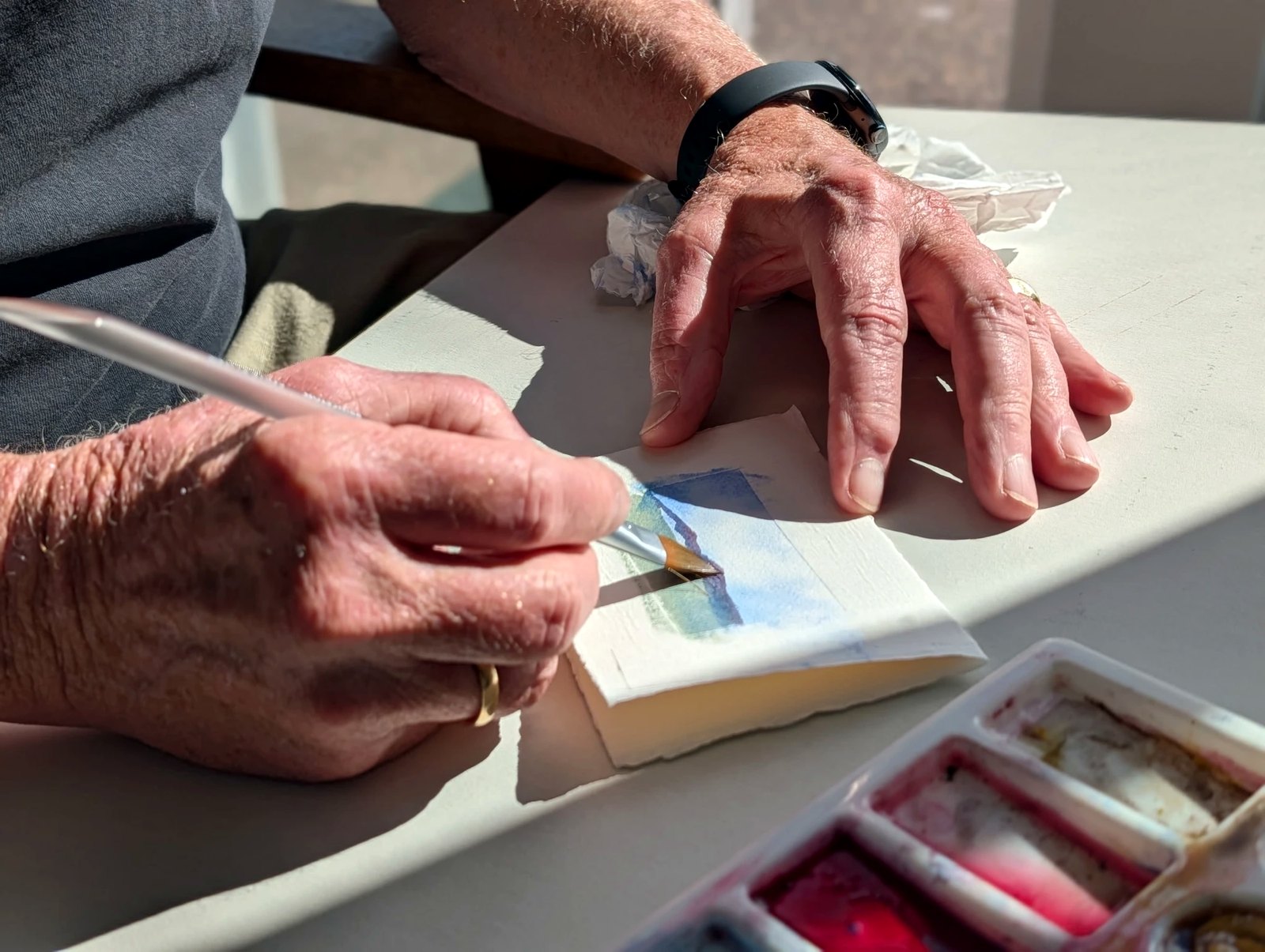 Richard's hands mixing a wash and painting a small landscape card